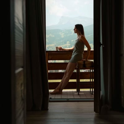Donna che beve il caffè nel terrazzo della sua camera a Casa Guargnè Cortina d’Ampezzo